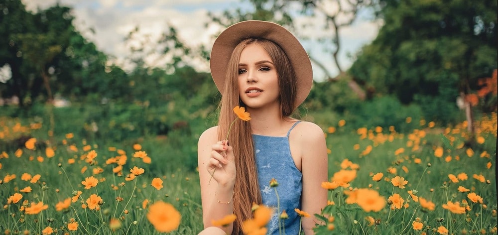 woman with beautiful healthy skin sitting on a filed with flowers